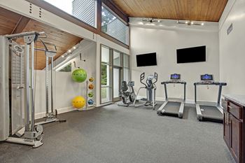 A home gym with a variety of equipment including treadmills, weights, and exercise balls.